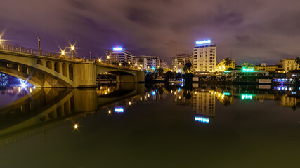 Fototapeta na wymiar Río Guadalquir en Sevilla, puente sobre el río con edificios al fondo iluminados en una noche lluviosa de invierno.