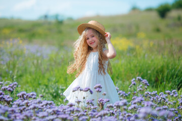 little girl in a straw hat in a field of purple flowers rejoice	