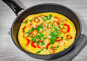 omelet with mushrooms, and vegetables in a frying pan