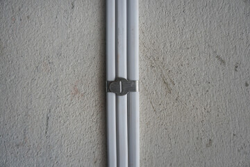 White electric cable attach on wall with 
aluminum cable clip. PVC insulated electrical wiring. With strap belt