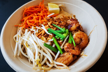 Asian dish Pad Thai prepared with noodles, grilled shrimps, soy sprouts, carrots pieces and sprinkle with peanuts to serve a delicious meal