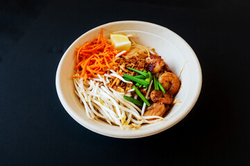 Asian dish Pad Thai prepared with noodles, grilled shrimps, soy sprouts, carrots pieces and sprinkle with peanuts to serve a delicious meal