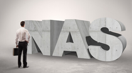 Rear view of a businessman standing in front of NAS abbreviation, modern technology concept