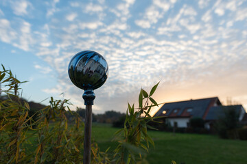 Gartenkugel vor Wolken und blauem Himmel Am Abend mit Haus und Bambusblättern