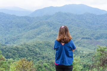 Naklejka na ściany i meble Back view of lonely freedom traveler adult woman standing on the top view of mountains enjoying beautiful nature sunrise and relaxing in the mountains at sunset at Nan, Thailand. Positive concept