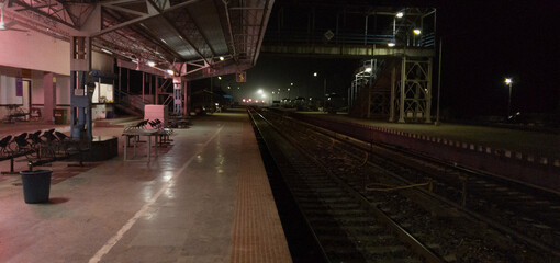 Empty railway platform at night with no people around.