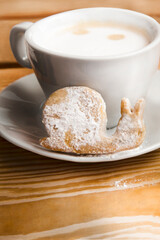 coffee drink in a white mug on a plate with a cake in the form of a snail, сlose, on a wooden surface, vertical image, nobody