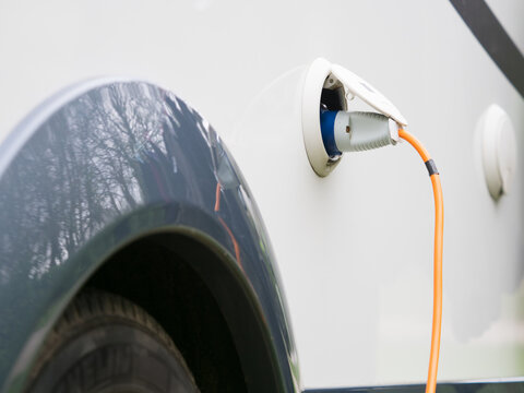 An orange cable is plugged into the electric hook up point on a motorhome recreational vehicle