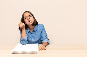 young woman feeling angry, annoyed, rebellious and aggressive, flipping the middle finger, fighting...