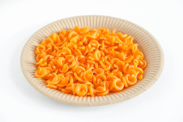 Orange pasta in a disposable paper plate on a white background. Top view. Copy, empty space for text