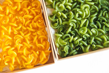 Pasta yellow and green in a cardboard box on a white background. Top view. Copy, empty space for text