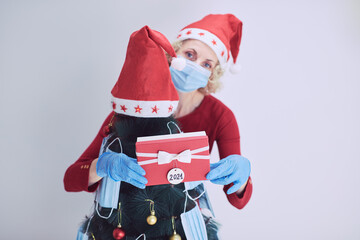 Woman  decorating christmas tree with medical masks during virus pandemic 2020 / 2021.