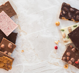 White, milk and dark chocolate with nuts and berries on the marble background with copy space, top view