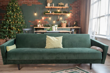 Christmas studio interior in white colors during daytime with a chester style sofa, Christmas tree with presents, chest of drawers and two widows at the background
