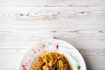 Pasta with Bolognese sauce, cheese and spices in a large white plate on a white wooden background