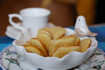 Beautiful shortbread cookies in a bowl with a bird and a white сup of coffee in the background