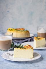 Lemon vanilla cheesecake decorated with rosemary, mint and lemon slices. Ricotta no crust cheesecake or casserole. Blue background.