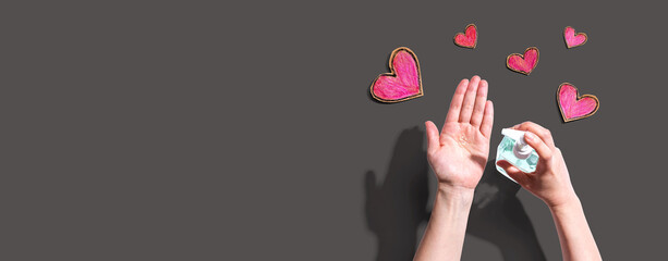 Applying sanitizer gel for cleaning hands with heart drawings