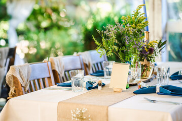 Outdoor wedding table decoration with fresh flowers and blank table cards. Special event table set...