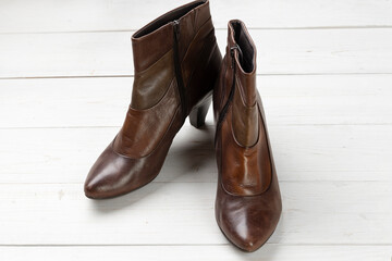 Women's autumn leather shoes on a white wooden table. Composition of clothes.