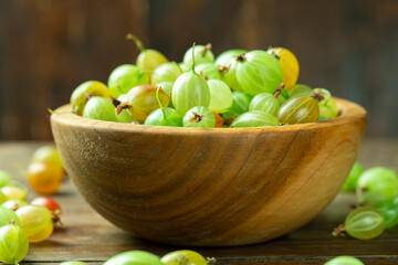 Sweet fresh gooseberry berry in a bowl on wood background.