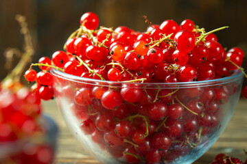 Sweet fresh red currant in a plate on wood table.