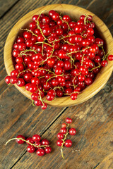 Sweet fresh red currant in a plate on wood table.