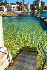 Metal stair going down in the transparent water of the rocky pool at Sydney Manly suburb with...