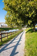Pathway, foot path next to a river leading under a brige, in calm suburbian town a sunny summer day, out running, walking traveling, 