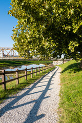 Pathway, foot path next to a river leading under a brige, in calm suburbian town a sunny summer day, out running, walking traveling, 