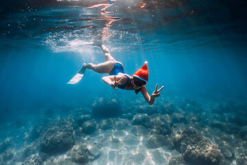 Christmas holidays party with freediver. Happy freediver woman with New year cap glides underwater...