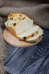 Focaccia bread with olives and sun-dried tomatoes. Linen is nearby. On pine boards.