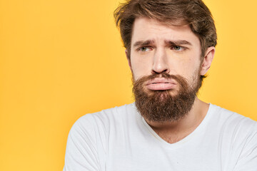 Obraz premium Man in white t-shirt emotions studio gestures with hands displeased facial expression yellow background