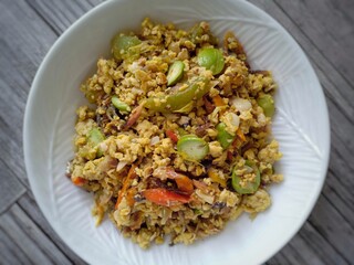 Indonesian food. Flat Lay of scrambled peda or salted fish with omelette. Served with tomatoes, slices of red chilli and petai or stinky beans. It tastes spicy. Very unique food