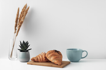 Blue mug and croissants on a white background. Eco-friendly and natural materials in the decor, dessert. Copy space, mock up.