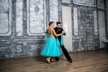Fototapeta na wymiar young couple in evening dance costumes dancing tango in the ballroom