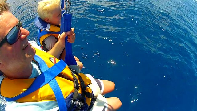 Father & Son are dipped & dragged through blue Pacific Ocean while parasailing in Maui, Hawaii, 4k GoPro- not stabilized