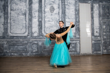 young couple in evening dance costumes dancing tango in the ballroom