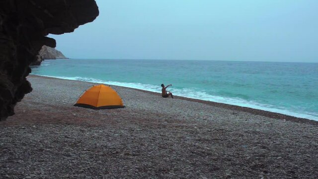 An adventure Moroccan man sitting on the front of his tent in Tikkit beach, Houceima, Morocco. camping in one the beautiful beaches in Morocco.