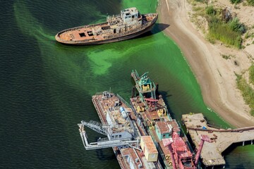 Top aerial view of old port equipment and  corroded ship in empty river cargo port of Ulyanovsk....