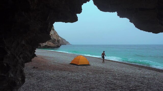 An adventure Moroccan man getting out of his tent to swim in Tikkit Beach, Houceima. Morocco. camping in a beautiful beach in Morocco.