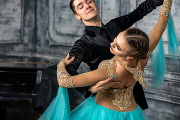 young couple in evening dance costumes dancing tango in the ballroom