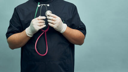 Young male doctor in professional clothes and with a stethoscope on a light blue background.