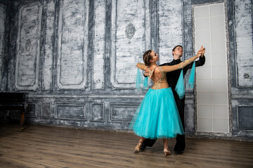 Obraz premium young couple in evening dance costumes dancing tango in the ballroom