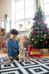 Obraz premium Young pretty female in casualwear looking at funny dog in knitted headwear