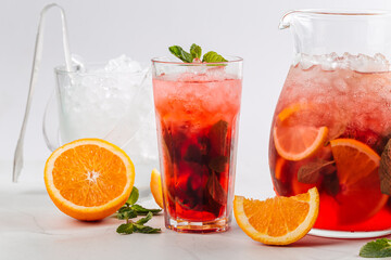 Side view on red berry lemonade in a jug and glass