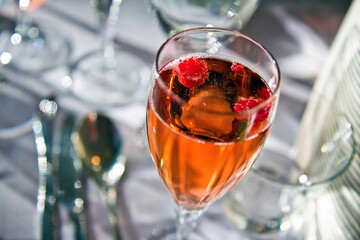 Closeup view of glass of delicious currant pink champagne with raspberry in it. .