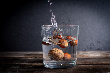 Frutos secos nueces y avellanas metidas en vaso con agua haciendo splash,  altas en grasas saludables