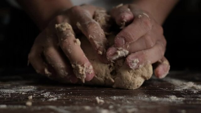 Slow Motion shot of  bakery chef kneeding dough on wooden table. Baking concept.