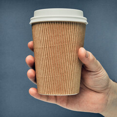 Paper cup in hand on a colored background. Eco-friendly materials in a coffee shop, biodegradable disposable tableware. Close up